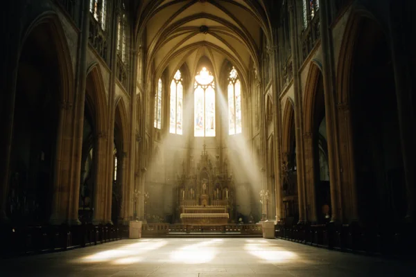 Interior of a Gothic cathedral with sunlight streaming through stained glass windows, illuminating the stone floor and altar.