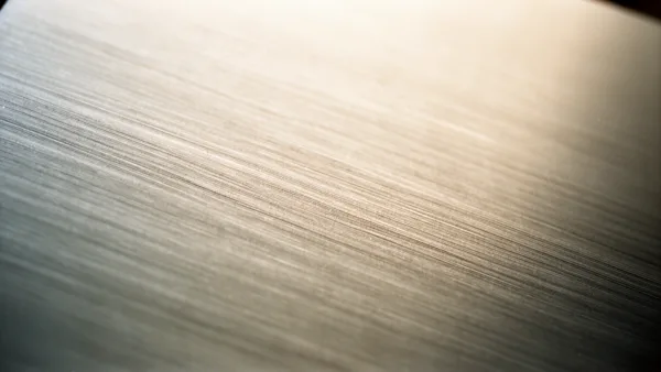 Close-up of a brushed metal surface with fine linear patterns and a warm gradient lighting.