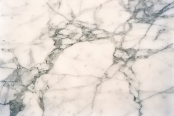 Close-up of white marble texture with gray veins under soft lighting.