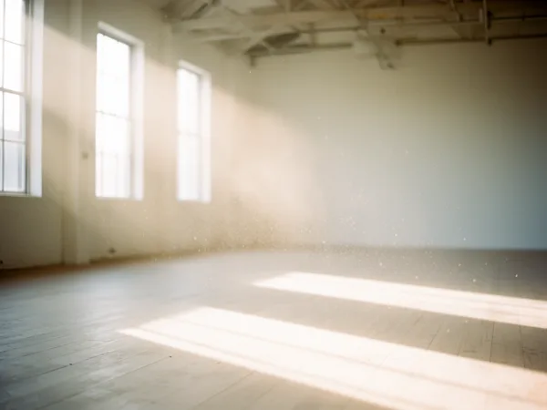 Sunlit empty room with floating dust particles, large windows, and wooden floor in soft natural light.
